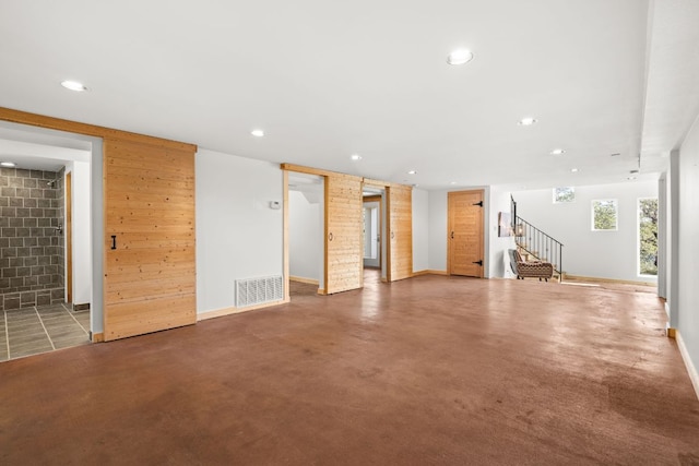 unfurnished living room featuring stairs, recessed lighting, baseboards, and concrete floors