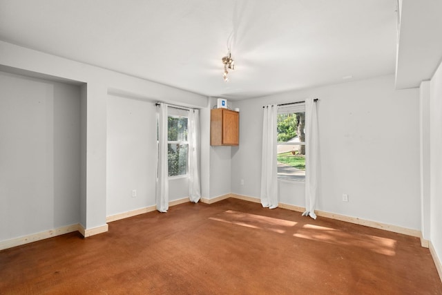 empty room with healthy amount of natural light, baseboards, and carpet flooring