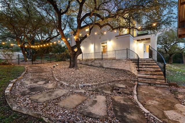 view of home's exterior featuring a balcony, stairway, stucco siding, and fence