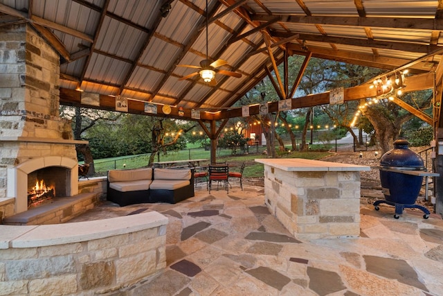 view of patio with a gazebo, ceiling fan, an outdoor living space with a fireplace, and fence