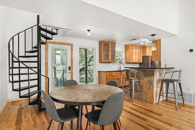 dining room with light wood-style floors, stairs, and baseboards