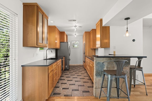 kitchen featuring a sink, baseboards, dark countertops, glass insert cabinets, and a breakfast bar