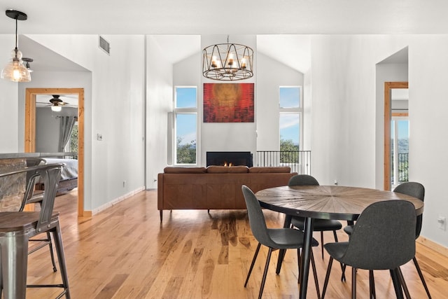 dining space featuring baseboards, vaulted ceiling, light wood finished floors, and plenty of natural light