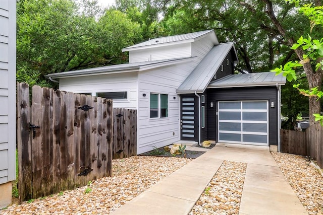 1314 Delano St Unit B, Austin, TX 78721 - view of front facade with concrete driveway, an attached garage, fence, and metal roof