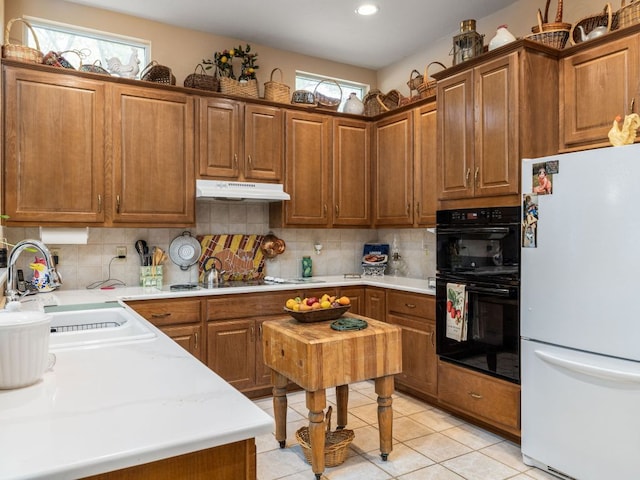 101 Chickadee Cv, Georgetown, TX 78633 - kitchen featuring freestanding refrigerator, a sink, under cabinet range hood, backsplash, and light countertops