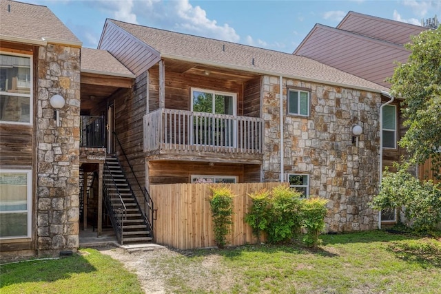 back of property featuring stone siding, stairway, and roof with shingles