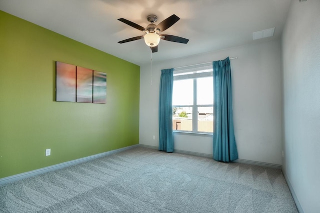 carpeted spare room with ceiling fan and baseboards