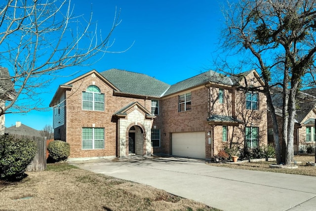 traditional-style house featuring brick siding, an attached garage, concrete driveway, and fence