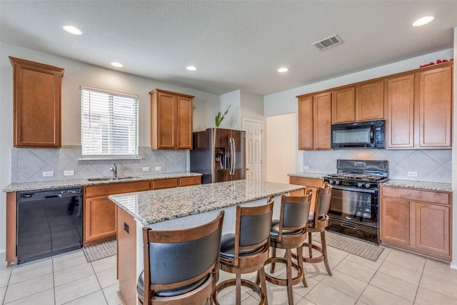 11905 Reindeer Dr, Austin, TX 78754 - kitchen with black appliances, a sink, a kitchen island, brown cabinets, and light tile patterned floors