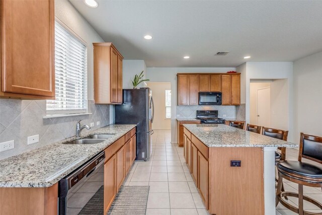 11905 Reindeer Dr, Austin, TX 78754 - kitchen featuring black appliances, a sink, a center island, a kitchen breakfast bar, and tasteful backsplash
