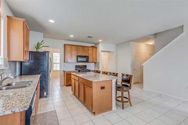 11905 Reindeer Dr, Austin, TX 78754 - kitchen with black microwave, stove, a sink, backsplash, and a kitchen bar