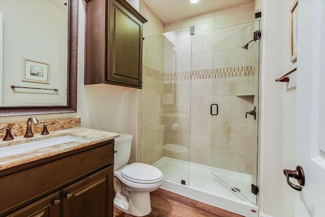 full bath featuring toilet, a shower stall, wood finished floors, and vanity