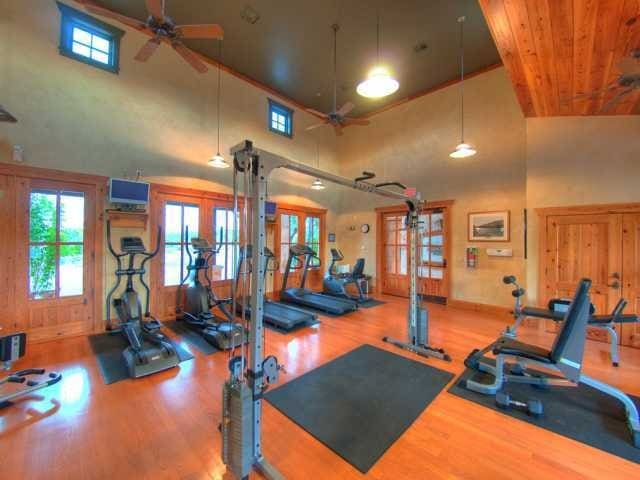 exercise room with a ceiling fan, wood finished floors, high vaulted ceiling, and baseboards
