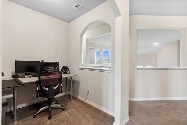 carpeted office featuring arched walkways and baseboards