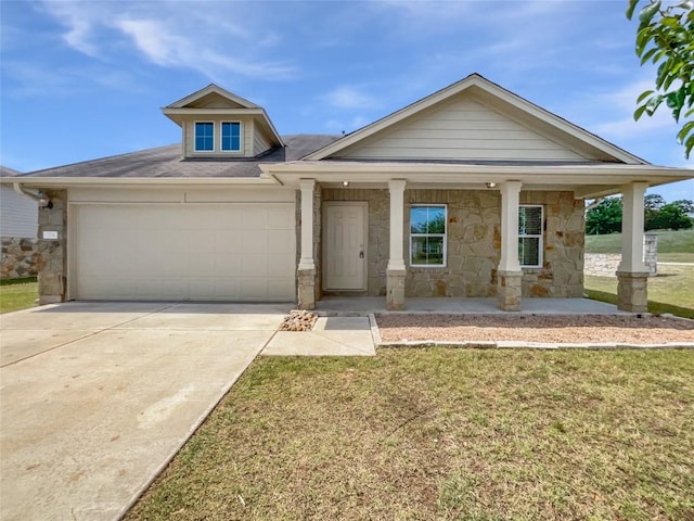324 Pack Horse Dr, Bastrop, TX 78602 - view of front facade featuring stone siding, a garage, concrete driveway, a front lawn, and covered porch