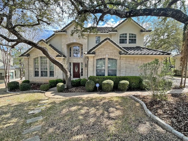 french provincial home with stone siding and a tiled roof
