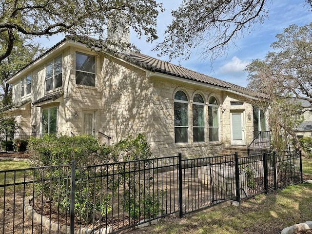 view of home's exterior with stone siding, a chimney, and a tile roof