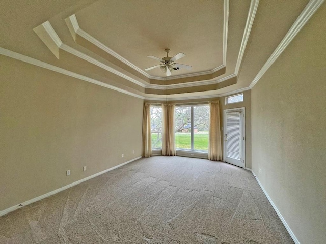 carpeted empty room with a raised ceiling, crown molding, ceiling fan, and baseboards