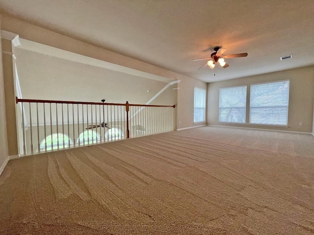 carpeted empty room featuring ceiling fan and baseboards
