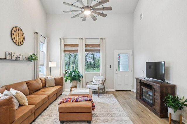 2024 Cantonata Dr, Leander, TX 78641 - living room featuring a high ceiling, ceiling fan, light wood-style flooring, and a glass covered fireplace