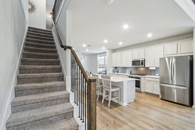 2024 Cantonata Dr, Leander, TX 78641 - kitchen featuring stainless steel appliances, backsplash, light wood-type flooring, a center island, and white cabinets