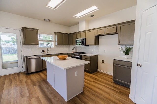 1420 Marsh Harbour Dr, Round Rock, TX 78664 - kitchen with appliances with stainless steel finishes, a sink, decorative backsplash, a center island, and dark wood-style flooring