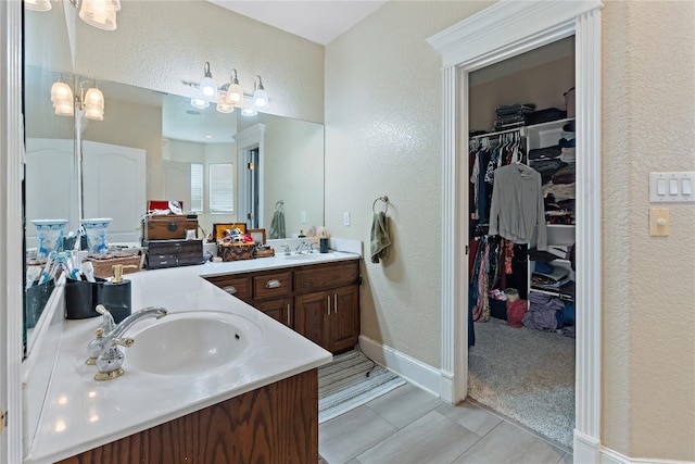 3424 S Old Bastrop Hwy, San Marcos, TX 78666 - full bathroom with a textured wall, double vanity, a spacious closet, and baseboards