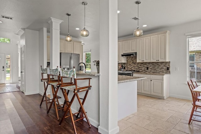 21016 Penny Royal Dr, Pflugerville, TX 78660 - kitchen featuring stainless steel appliances, under cabinet range hood, backsplash, light stone countertops, and baseboards