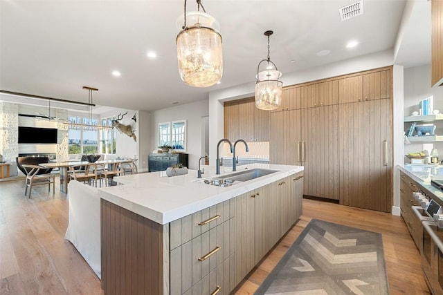 kitchen featuring a sink, open floor plan, a large island, light wood-type flooring, and recessed lighting
