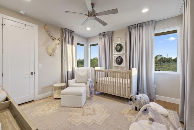 bedroom featuring baseboards, recessed lighting, a ceiling fan, wood finished floors, and a crib