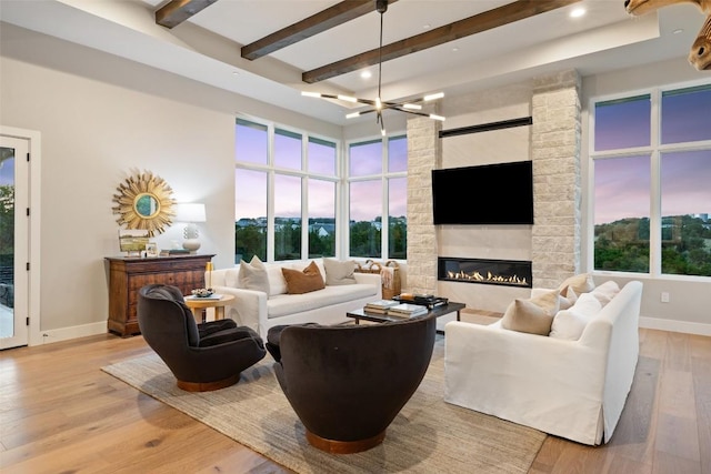 living area with baseboards, beamed ceiling, light wood-style flooring, recessed lighting, and a stone fireplace