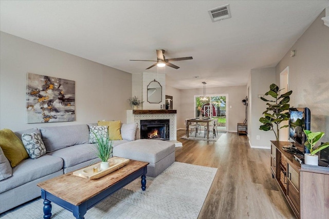 7605 Hawkeye Dr, Austin, TX 78749 - living room featuring light wood-style floors, a ceiling fan, baseboards, and a fireplace