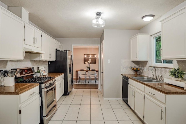 7605 Hawkeye Dr, Austin, TX 78749 - kitchen featuring stainless steel appliances, a sink, dark countertops, under cabinet range hood, and white cabinets