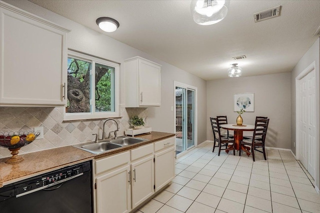 7605 Hawkeye Dr, Austin, TX 78749 - kitchen with black dishwasher, decorative backsplash, light tile patterned floors, and white cabinets