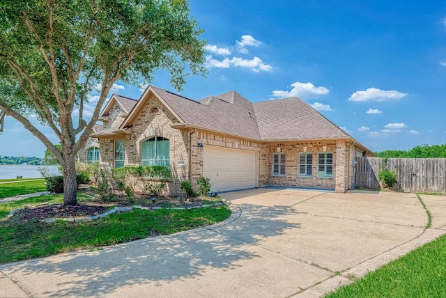 13403 Lakemeade Ct, Sugar Land, TX 77498 - french country home featuring fence, concrete driveway, an attached garage, brick siding, and roof with shingles