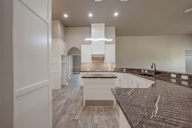 13403 Lakemeade Ct, Sugar Land, TX 77498 - kitchen featuring a sink, a center island, arched walkways, tasteful backsplash, and light wood-style floors