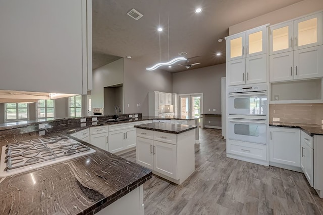 13403 Lakemeade Ct, Sugar Land, TX 77498 - kitchen featuring gas stovetop, white double oven, white cabinetry, recessed lighting, and glass insert cabinets