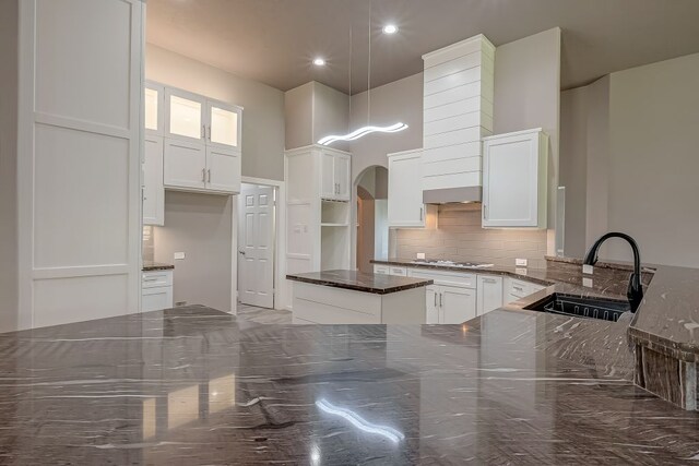 13403 Lakemeade Ct, Sugar Land, TX 77498 - kitchen with a sink, backsplash, dark stone countertops, stainless steel gas stovetop, and arched walkways