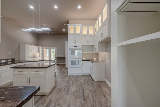 13403 Lakemeade Ct, Sugar Land, TX 77498 - kitchen with white double oven, light wood-style flooring, recessed lighting, glass insert cabinets, and white cabinets