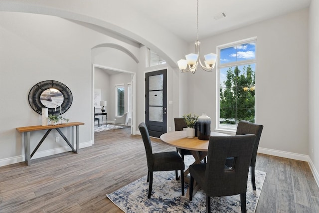 dining area with a chandelier, healthy amount of natural light, arched walkways, and baseboards