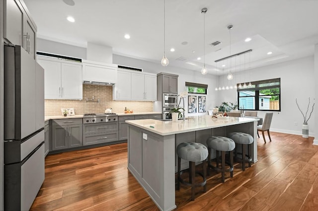 3102 Hunt Trl, Austin, TX 78757 - kitchen with appliances with stainless steel finishes, gray cabinets, dark wood-style floors, light countertops, and backsplash