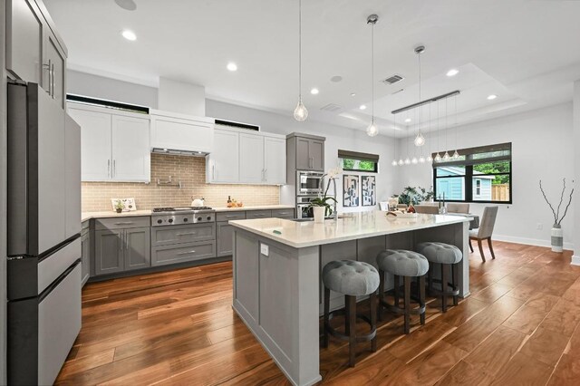 3102 Hunt Trl, Austin, TX 78757 - kitchen with stainless steel appliances, gray cabinets, dark wood-style flooring, light countertops, and backsplash