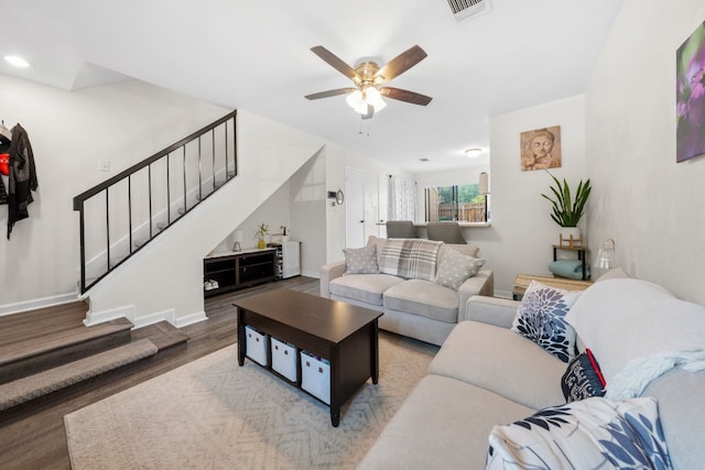 living area with stairs, wood finished floors, ceiling fan, and baseboards