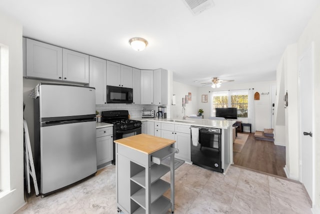 kitchen with black appliances, a sink, gray cabinetry, a peninsula, and open shelves