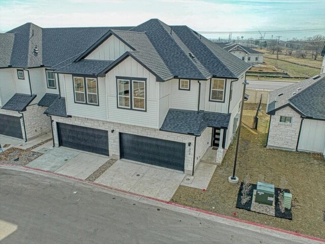 2600 Gattis School Rd Unit 401, Round Rock, TX 78664 - view of front of house with board and batten siding, a garage, roof with shingles, concrete driveway, and stone siding