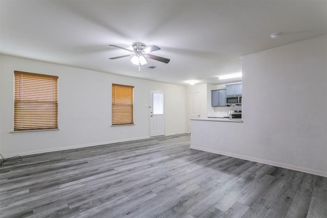 unfurnished living room featuring a ceiling fan, dark wood finished floors, a sink, and baseboards