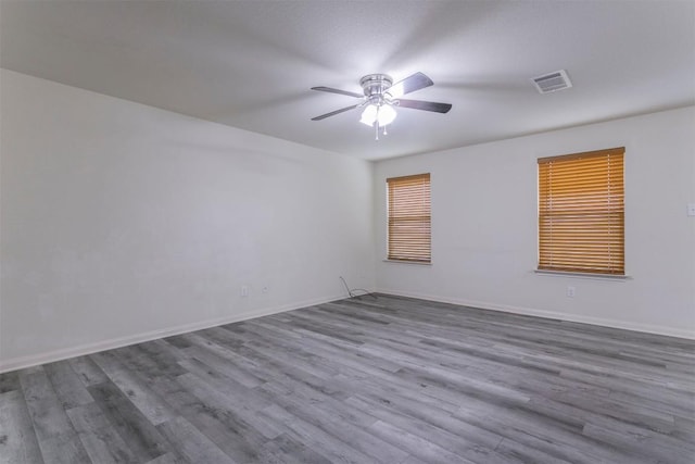 unfurnished room with wood finished floors, a ceiling fan, and baseboards