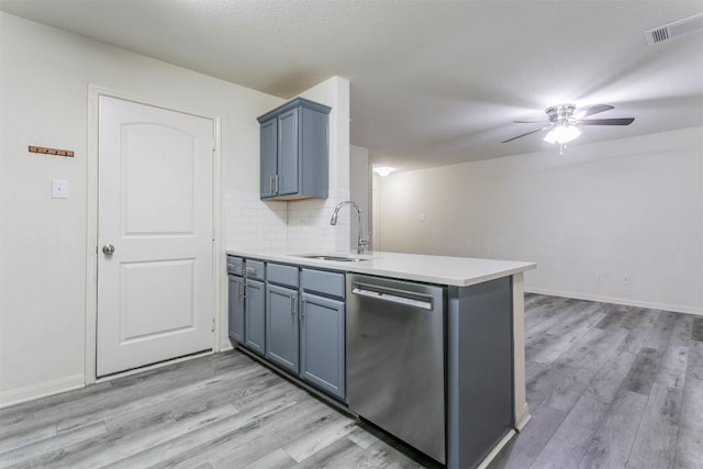 kitchen with stainless steel dishwasher, a sink, ceiling fan, a peninsula, and light wood-type flooring