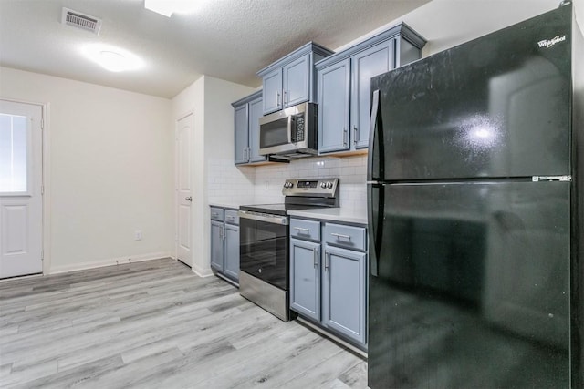 kitchen with stainless steel appliances, light wood-style flooring, tasteful backsplash, light countertops, and baseboards