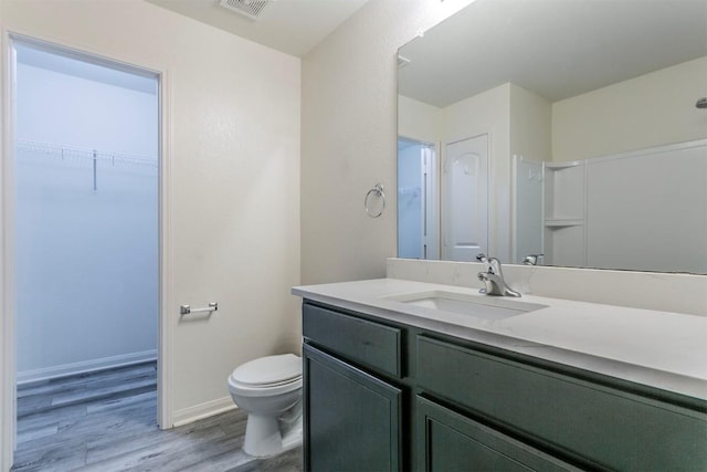 bathroom with wood finished floors, toilet, vanity, and baseboards